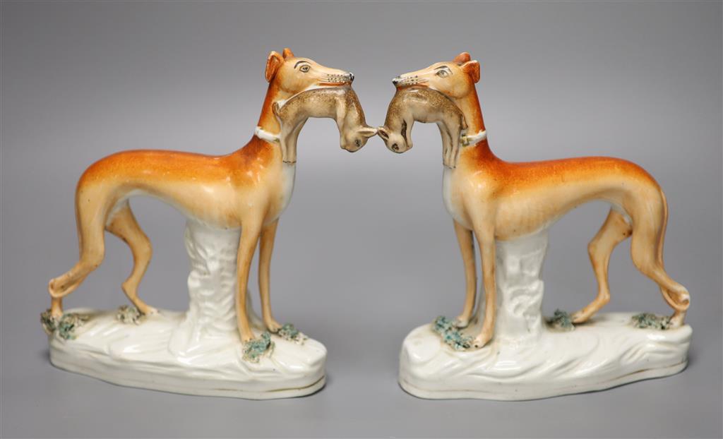 A pair of 19th century Staffordshire pottery greyhound figures, each with prey, 19cm high, 16.5cm long